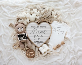 Könnte beinhalten: Ein weißer Strampler mit dem Text "Baby McKinney" und einem Herz, ein brauner Teddybär, der ein Ultraschallbild hält, ein Holzschild mit dem Text "We can't wait to meet you" und "September 2025" sowie ein Holzschild mit dem Text "Hello World".