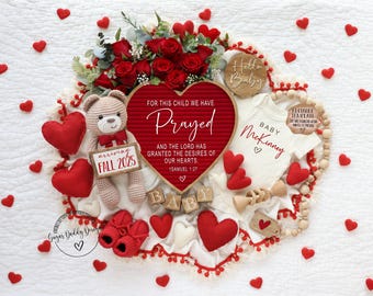 May include: A red heart-shaped letter board with the text "For this child we have prayed and the Lord has granted the desires of our hearts. 1 Samuel 1:27" surrounded by red hearts, a teddy bear, a baby onesie, and wooden blocks that spell "baby".