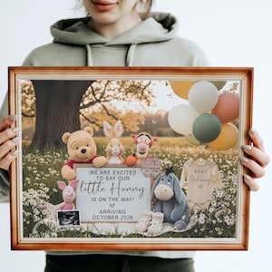 May include: A framed announcement featuring Winnie the Pooh characters, balloons, and baby clothes. The sign reads "We are excited to say our little Hunny is on the way! Arriving October 2026."