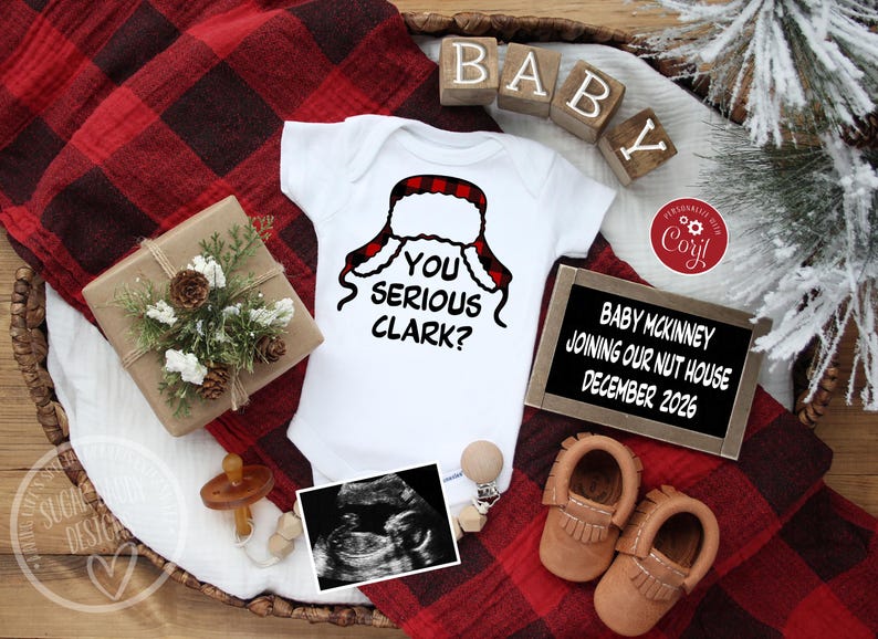 May include: A white baby onesie with a red and black plaid hat design and the text "YOU SERIOUS CLARK?". The image includes a gift box, baby shoes, ultrasound image, and a sign that reads "BABY MCKINNEY JOINING OUR NUT HOUSE DECEMBER 2026".