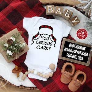 May include: A white baby onesie with the phrase "YOU SERIOUS CLARK?" and a red and black plaid hat design. The image includes baby shoes, a pacifier, and a sign that reads "BABY MCKINNEY JOINING OUR NUT HOUSE DECEMBER 2026."