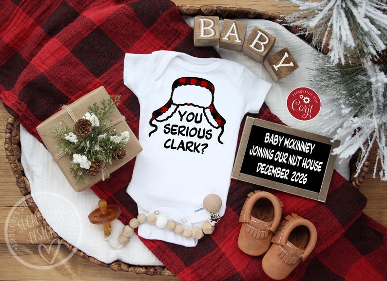 May include: A white baby onesie with the phrase "YOU SERIOUS CLARK?" and a red and black plaid hat design. The image includes baby shoes, a pacifier, and a sign that reads "BABY MCKINNEY JOINING OUR NUT HOUSE DECEMBER 2026."
