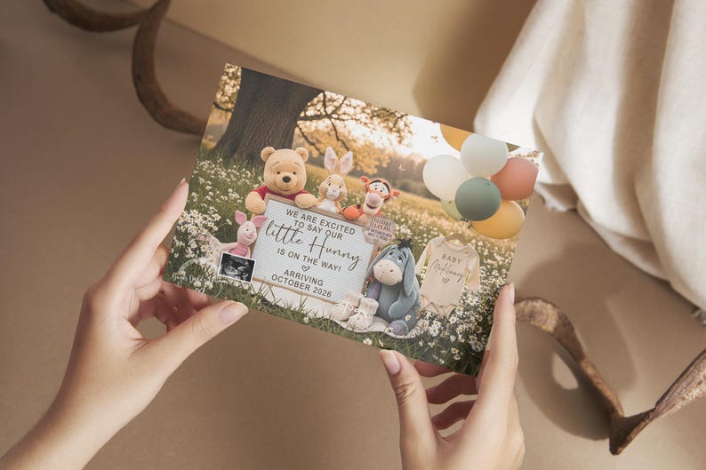 May include: A baby announcement card featuring Winnie the Pooh characters. The card includes the text "We are excited to say our little Hunny is on the way! Arriving October 2026." Balloons and a baby onesie are also visible.