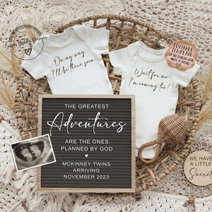May include: A black letter board with the text "The Greatest Adventures Are The Ones Planned By God" and "McKinney Twins Arriving November 2023". Two white baby onesies with the text "On my way I'll be there soon" and "Wait for me I'm coming too!" are in a wicker basket with a wooden rattle. A small wooden circle with the text "We Have A Little Secret" is on a white fuzzy surface.