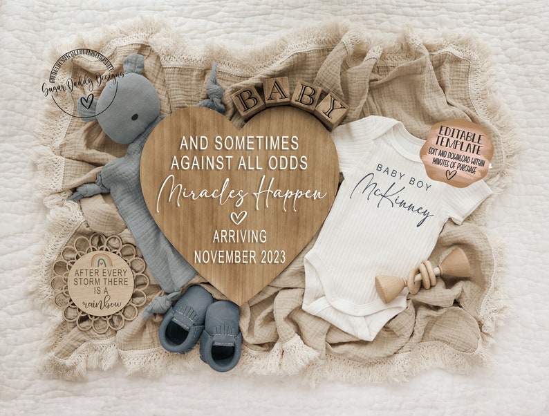 May include: A wooden heart-shaped sign with the text "And sometimes against all odds miracles happen" and "Arriving November 2023". A white onesie with the text "Baby Boy McKinney" is next to the sign. A wooden toy and a blue baby shoe are also in the image.