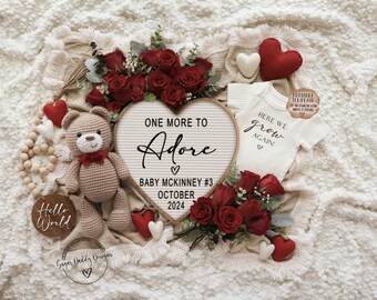 Op de afbeelding: Een hartvormig bord met de tekst "One More to Adore" en "Baby McKinney #3 October 2024" omringd door rode rozen, een gehaakte teddybeer, een houten bord met de tekst "Hello World" en een witte romper met de tekst "Here We Grow Again".