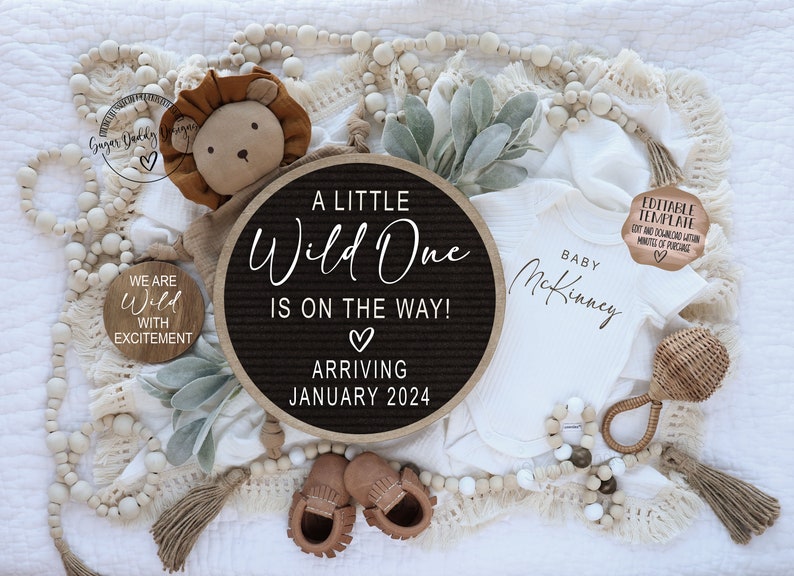 Peut inclure: Un tableau d'affichage noir et blanc avec le texte "A Little Wild One Is On The Way! Arriving January 2024". Une grenouill&egrave;re blanche avec le texte "Baby McKinney" est &agrave; c&ocirc;t&eacute; du tableau d'affichage. Un lion en peluche, un petit hochet en bois et une guirlande de perles en bois sont &eacute;galement pr&eacute;sents sur l'image.