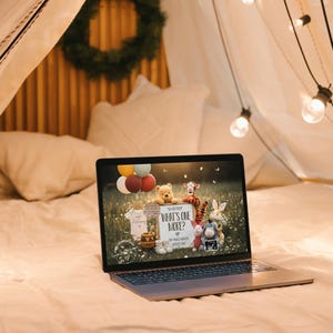May include: A laptop displaying a baby shower invitation with Winnie the Pooh characters, balloons, and the text "What's One More?". The laptop is on a bed, surrounded by fairy lights and pillows.