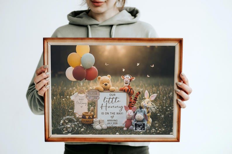 May include: A framed image featuring Winnie the Pooh characters, balloons, and baby items. The sign reads "Our little Hunny is on the way!" with an arrival date of July 2028. The image is held by a person.