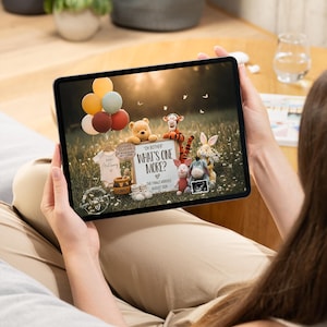 May include: A tablet displays a pregnancy announcement featuring Winnie the Pooh characters. The announcement includes a sign that reads "What's One More?" with the expected arrival date. Balloons and baby clothes are also visible.
