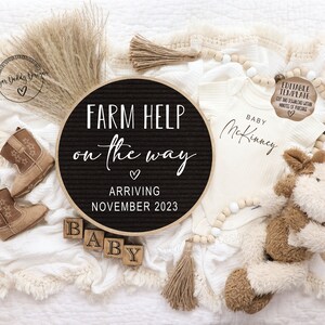 May include: A black and white letter board with the text "FARM HELP on the way" and "ARRIVING NOVEMBER 2023". A white onesie with the text "BABY McKinney" is next to the letter board. There are brown cowboy boots, wooden blocks that spell "BABY", and a stuffed cow toy.