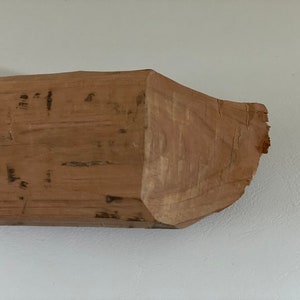 Könnte beinhalten: Ein Stück grob behautem Holz in natürlicher, hellbrauner Farbe und leicht unregelmäßiger Form.