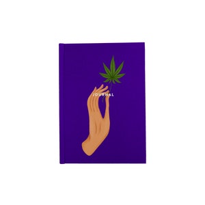 May include: Purple journal with a hand holding a green cannabis leaf and the word "JOURNAL" printed on the cover.