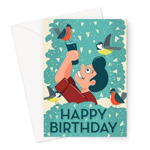 May include: A birthday card featuring a cartoon illustration of a person holding a camera with birds flying around them. The card has a blue and green background with white polka dots and the text "Happy Birthday".