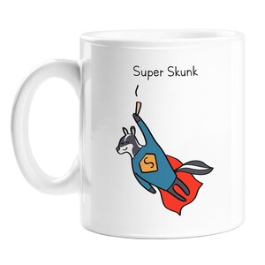 May include: White ceramic mug featuring a cartoon illustration of a skunk dressed as a superhero, flying with a red cape. The text "Super Skunk" is printed on the mug.