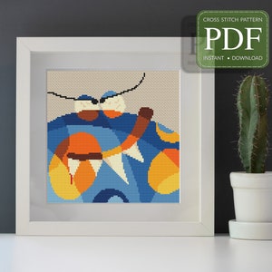 Könnte beinhalten: Ein Kreuzstichmuster mit einem farbenfrohen abstrakten Design mit blauen, orangen und gelben Formen. Das Muster ist gerahmt und an einer weißen Wand ausgestellt.