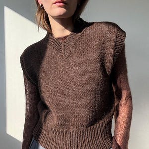 Pode incluir: Um colete de malha marrom sem mangas com decote em V.