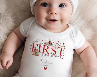 May include: White baby onesie with a red and green Christmas design that says "My First Christmas" with a red heart and the name "Freddie" and the year "2023" printed below.
