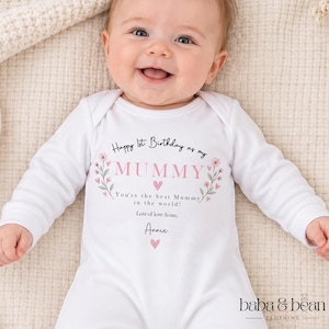 May include: A white long-sleeved baby bodysuit featuring the text Happy 1st Birthday as my MUMMY, You're the best Mummy in the world!, Lots of love from, Annie, decorated with pink floral sprigs and small pink hearts on the chest area.