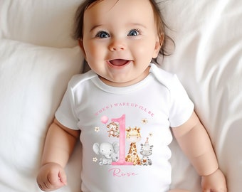 May include: A white onesie with a pink number one and the text "When I wake up I'll be" and the name "Rose". The number one is surrounded by a monkey, giraffe, elephant, and zebra.