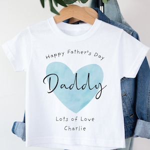 May include: White t-shirt with a blue watercolor heart that says "Daddy" inside. The text "Happy Father's Day" is above the heart and "Lots of Love Charlie" is below the heart.