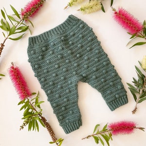 Puede incluir: Pantalones de bebé de crochet verde con un patrón texturizado de punto bobble.