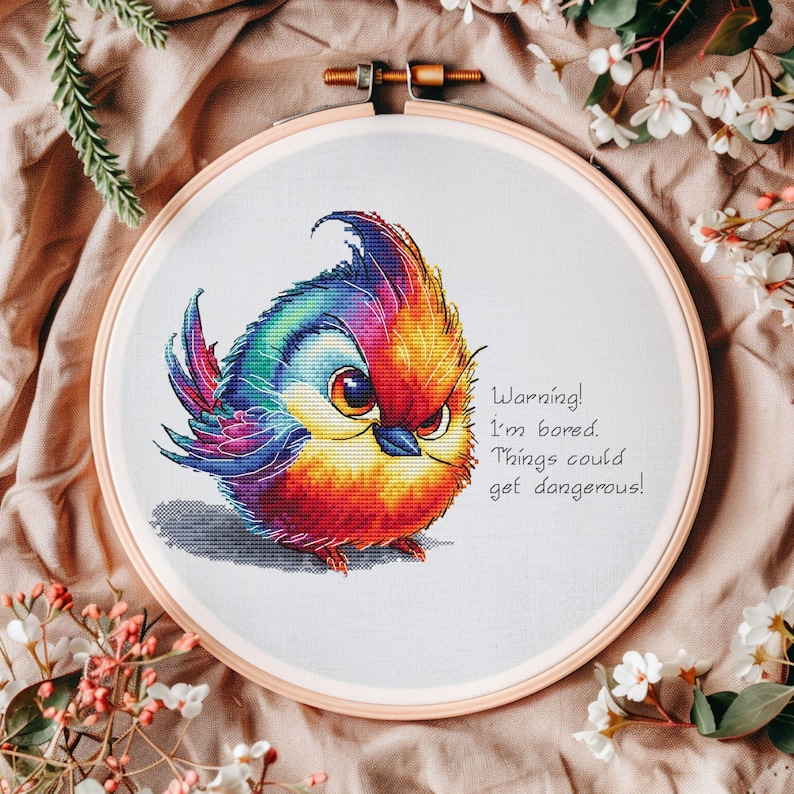 May include: A colorful cross-stitch embroidery of a cartoon bird with the text "Warning! I'm bored. Things could get dangerous!"