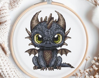 May include: A cross-stitch embroidery of a cute, cartoon dragon with large, green eyes. The dragon is sitting on its hind legs with its wings spread out. The dragon is black with brown accents.