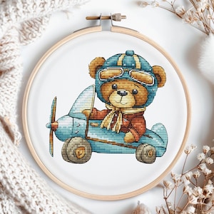 Schattig kruissteekpatroon pilootbeer. Digitaal patroon Kwekerijberoepen. Kaart met handborduurwerk teddybeervlieger