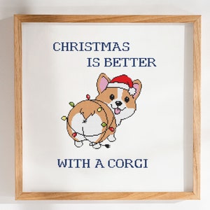 Puede incluir: Obra de arte de punto de cruz en un marco de madera. La imagen presenta un corgi de dibujos animados con un gorro de Papá Noel y luces navideñas. El texto dice "CHRISTMAS IS BETTER WITH A CORGI" en azul marino.