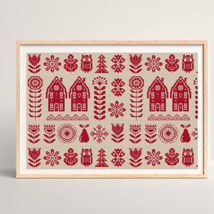 May include: A framed print featuring a repeating pattern of red cross-stitch style folk art. The design includes houses, flowers, owls, trees, and other decorative elements on a beige background. The frame is made of light-colored wood.