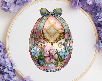 May include: A pink Easter egg with a gold trim and a blue bow. The egg is decorated with blue and pink flowers and green leaves.