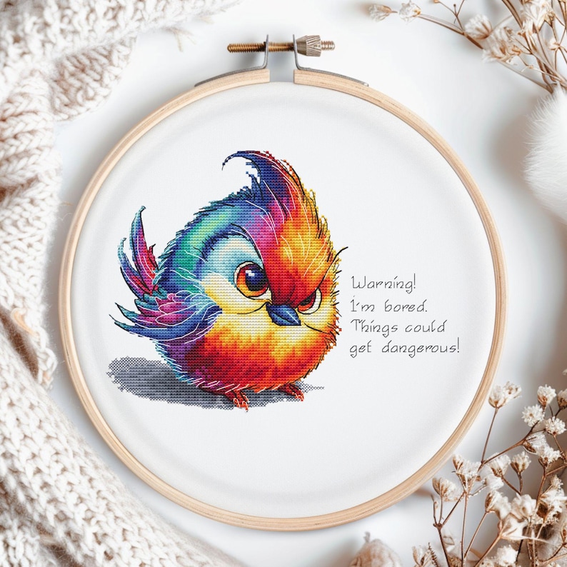 May include: A colorful cross-stitch embroidery of a cartoon bird with the text "Warning! I'm bored. Things could get dangerous!"