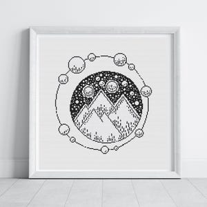 May include: Framed black and white cross-stitch artwork. The design is circular, featuring mountain peaks, stars, and surrounding orbs. The minimalist style is suitable for home decor. The frame is white and square.