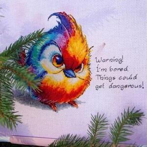 May include: A colorful cross-stitch embroidery of a bird with a warning message: "Warning! I'm bored. Things could get dangerous!"