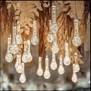 Pode incluir: Um grupo de lâmpadas de vidro transparente em forma de lágrima penduradas no teto, criando uma luminária caprichosa e elegante.