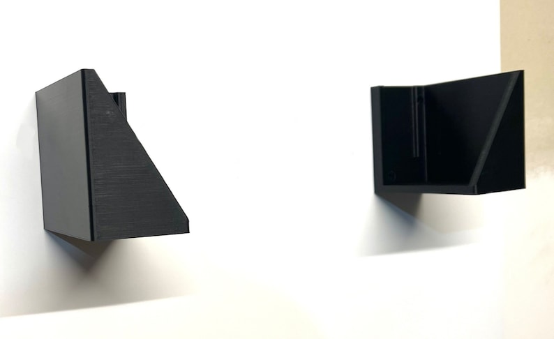 Puede incluir: Dos estanter&iacute;as de pared geom&eacute;tricas negras est&aacute;n montadas en una pared blanca. Las estanter&iacute;as tienen un dise&ntilde;o moderno y minimalista con lados angulados y una forma rectangular. Las estanter&iacute;as est&aacute;n hechas de un material oscuro y s&oacute;lido.