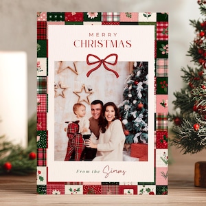 Puede incluir: Una tarjeta de Navidad con una foto familiar en el interior, enmarcada por un diseño de patchwork en rojo, verde y blanco. La tarjeta dice "Merry Christmas" con una ilustración de lazo. La familia sonríe frente a un árbol de Navidad.