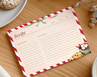 May include: A recipe card with a red and white striped border, featuring the word "Recipe" at the top. The card has lines for ingredients and directions, with a watercolor illustration of cookies and hot cocoa. A plate of cookies and a cup of coffee are also visible.