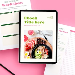 以下が含まれることがあります： デジタルタブレットには、「Ebook Title here」というテキストと食べ物の画像が表示された電子書籍の表紙が表示されています。「Self-Discovery Worksheet」と「Daily Planner」も表示されており、すべてピンク色の背景です。鉛筆が表面にあります。
