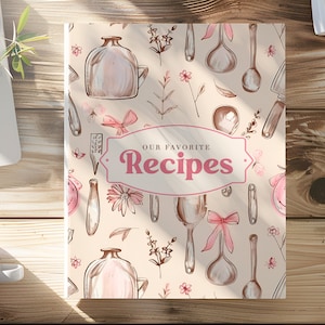 May include: A beige cookbook cover with a pink and brown floral pattern. The cover features a title that reads "Our Favourite Recipes" in a pink, cursive font.