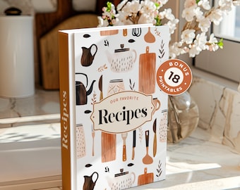May include: A white cookbook with a brown spine and the text "Our Favorite Recipes" on the cover. The cover features a pattern of kitchen utensils, teapots, and other kitchen items in brown, white, and black. A brown circle with the text "Bonus 18 Printables" is on the cover.