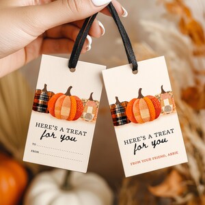 May include: Two rectangular cream-colored gift tags with black ribbon loops. Each tag features a row of three pumpkins in plaid and orange patterns. The text reads "HERE'S A TREAT for you" with "TO" and "FROM" lines on one, and "FROM YOUR FRIEND, ABBIE" on the other.