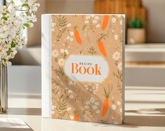 May include: A recipe book with a beige cover featuring a floral and carrot pattern. The book has a white spine and the words "RECIPE BOOK" in orange within a white frame. The background includes a vase of white flowers.