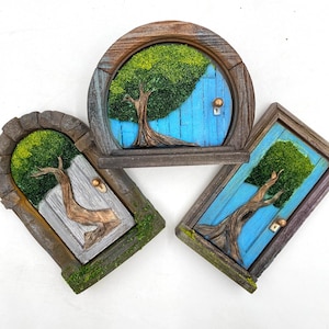May include: Three miniature fairy doors with a whimsical design. Each door features a tree and a blue or gray door. The frames are made of wood and have a rustic, mossy appearance. The doors are perfect for adding a touch of fantasy to any space.