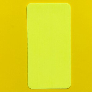 Op de afbeelding: Een rechthoekig, neongeel object met afgeronde hoeken, geplaatst tegen een effen gele achtergrond. De vorm van het object is een lange rechthoek en de kleur is een helder, levendig geel.