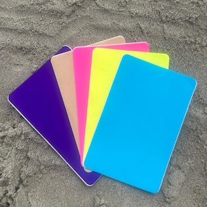 Op de afbeelding: Een verzameling kleurrijke rechthoekige kaarten in paars, beige, roze, geel en blauw. De kaarten hebben afgeronde hoeken en een witte rand, gerangschikt in een waaier tegen een neutrale achtergrond.