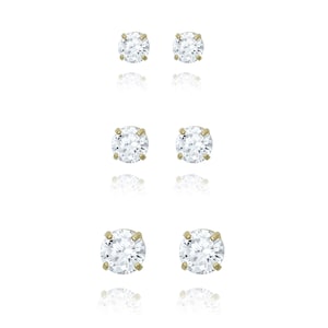May include: A set of three pairs of gold stud earrings with clear round cubic zirconia stones.