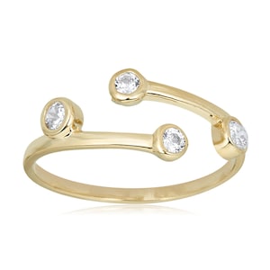 May include: A gold ring with four clear stones set in the band. The ring is open and wraps around the finger.