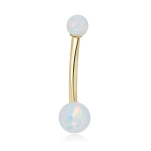 May include: A gold belly button ring with two white opal balls.